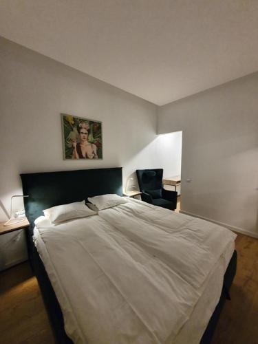 1 dormitorio con 1 cama grande y 1 silla en Smaragdo apartamentai, en Kaunas
