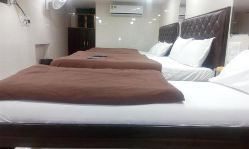 Hotel Qamar في مومباي: سريرين في غرفة الفندق مع بطانيات بنية