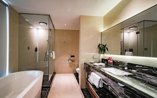 a bathroom with two sinks and a tub and a shower at Ramada Changzhou North Hotel in Changzhou