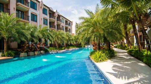 - une piscine bordée de palmiers à côté d'un bâtiment dans l'établissement Peaceful Pool-access room - Q seaside Hua Hin, à Phetchaburi