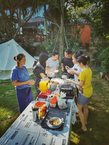 een groep mensen die rond een tafel met eten staan bij Camp NYS Campsite in Muaklek