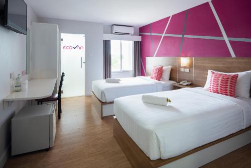 Habitación de hotel con 2 camas y escritorio en Eco Inn Lite Nakhon Si Thammarat en Nakhon Si Thammarat