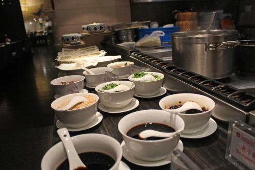 a line of bowls of food on a counter in a kitchen at Ramada Changzhou North Hotel in Changzhou