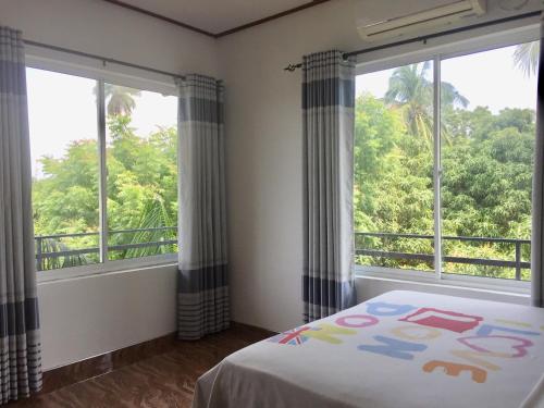 a bedroom with two windows and a bed with a bedspread at Thisara Guest House in Polonnaruwa