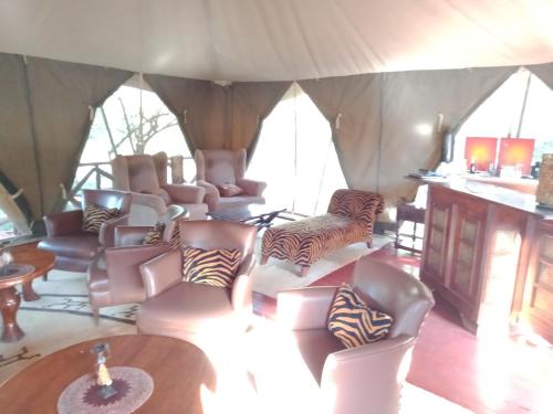 a living room with couches and chairs in a tent at Mara Ngenche Safari Camp - Maasai Mara National Reserve in Talek