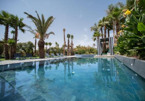 a swimming pool with trees and palm trees at Le Domaine Limoune in Oulad Teïma