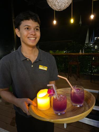 a man holding a tray with two drinks on it at The Scene Cliff View Villas in Ao Nang Beach