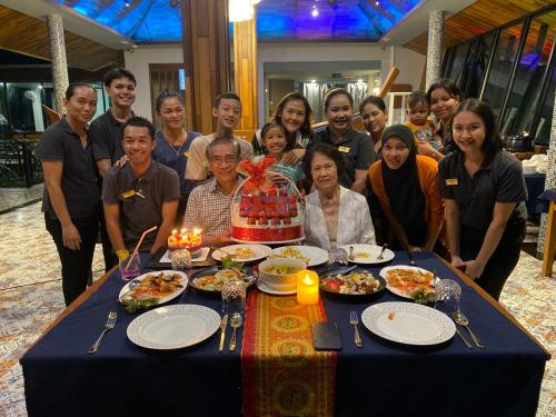 a group of people standing around a table with a cake at The Scene Cliff View Villas in Ao Nang Beach