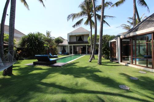 a house with a yard with a pool and palm trees at Villa Samudra Luxury Beachfront in Ketewel