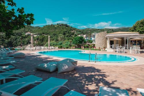 a swimming pool with blue lounge chairs and a resort at Anemolia Parga Suites in Sarakiniko