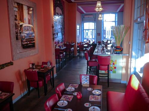 een restaurant met rode stoelen en tafels en een bar bij Hotel Oldenburg in Zwolle