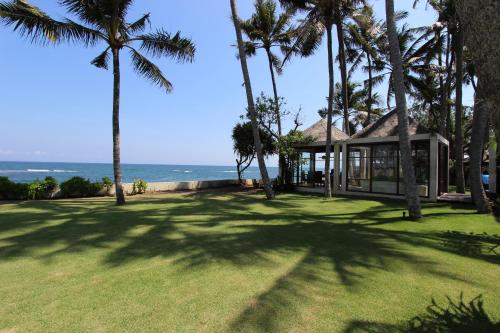 a house with palm trees in front of the ocean at Villa Samudra Luxury Beachfront in Ketewel