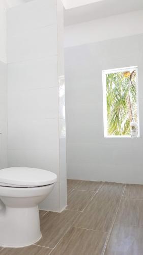 a white bathroom with a toilet and a picture at Lucky Spot Beach Bungalow in Song Cau