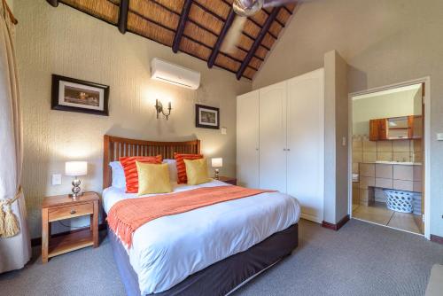 a bedroom with a large bed with orange and yellow pillows at Kruger Park Lodge Unit No. 524 in Hazyview