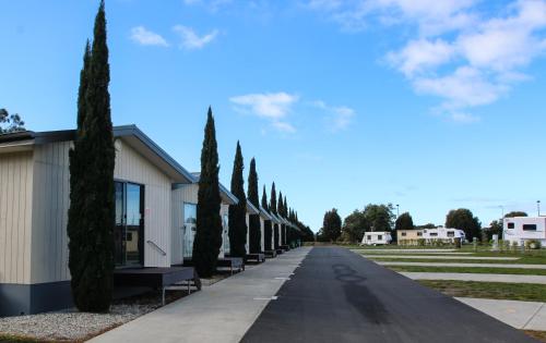 a row of cypress trees next to a building at BIG4 Hobart Airport Tourist Park in Cambridge