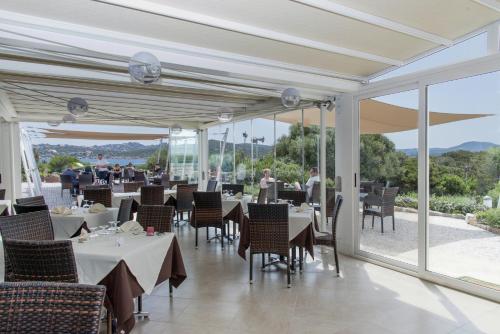 a dining room with tables and chairs and windows at Isola dei Gabbiani - Land of water in Porto Pollo