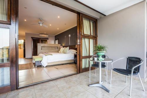 a bedroom with a bed and a table and chairs at One On Hely in Mtunzini