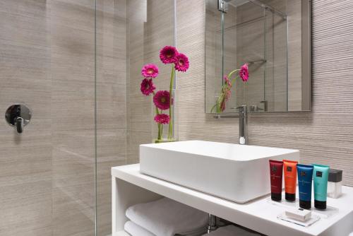 un bagno con lavandino bianco e fiori rosa di Hotel Glance In Florence a Firenze