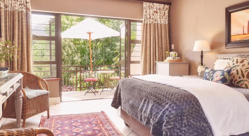 a bedroom with a bed and a balcony with a patio at Upper House Guesthouse in Clarens