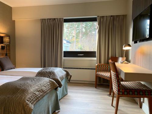 a hotel room with a bed and a desk and a window at Holmen Fjordhotell in Nesbru