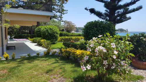 a garden in front of a house with flowers at Villa Sogno sulla Spiaggia in Fontane Bianche