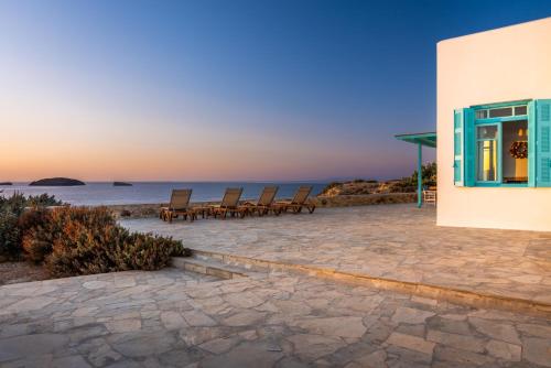 a group of chairs sitting on a patio near the ocean at Villa Zefyros in Pachaina