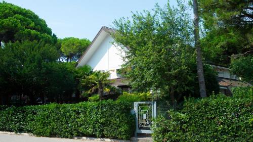 une maison blanche avec une clôture et des arbres dans l'établissement Villa Scultura Seaview, à Lignano Sabbiadoro