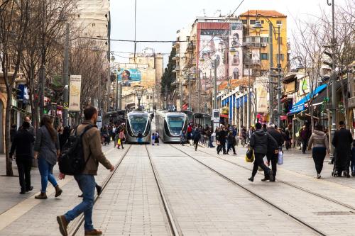 people walking on a busy city street with trains at The boutique in Jerusalem
