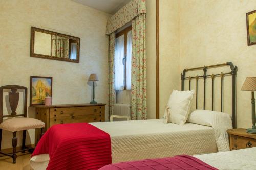 a bedroom with two beds and a chair and a mirror at Casa Rural El Capricho in Otero de Herreros
