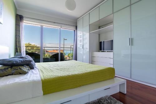 um quarto com uma cama e uma grande janela em Monumental Residence apartment with pool by HR Madeira no Funchal