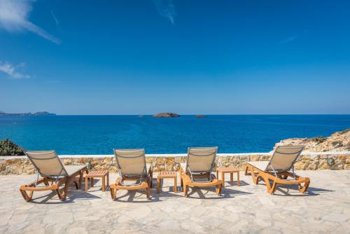 a group of chairs and tables next to the ocean at Villa Zefyros in Pachaina