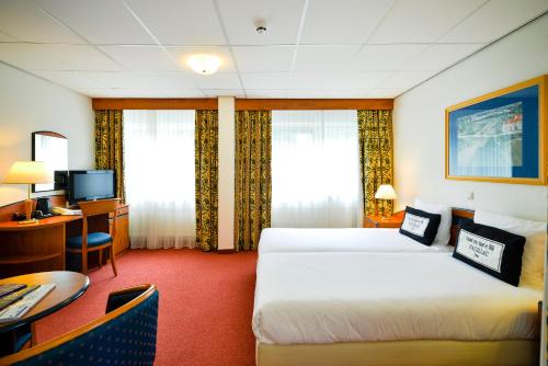 ein Hotelzimmer mit 2 Betten und einem Schreibtisch in der Unterkunft Fletcher Hotel Restaurant Beekbergen-Apeldoorn in Beekbergen