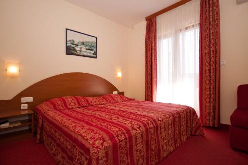ein Schlafzimmer mit einem roten Bett und einem Fenster in der Unterkunft HOTEL MEDUZA in Biograd na Moru