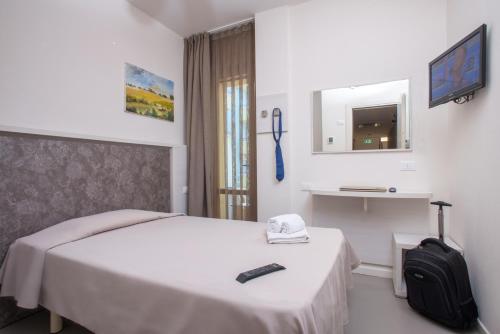 a hotel room with a bed and a backpack and a television at Hotel Maioli B&B in Misano Adriatico
