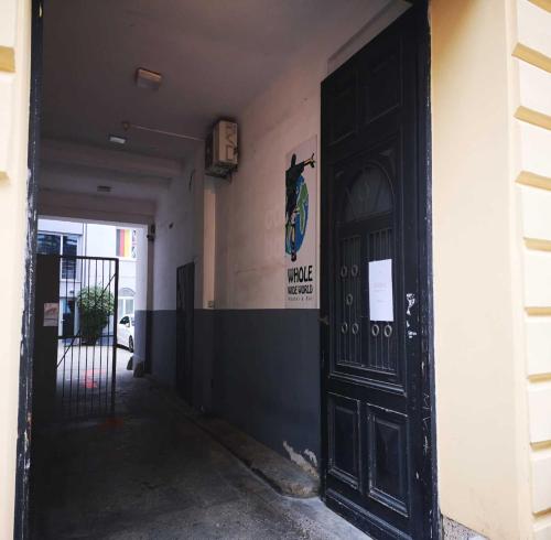 a black door to a building with a sign on the wall at Whole Wide World Hostel in Zagreb
