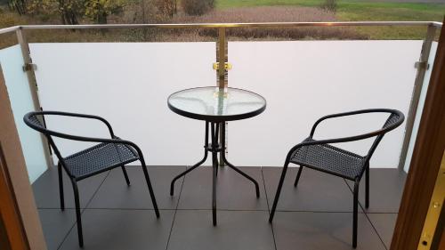 a glass table and two chairs on a balcony at Apartament Fibra Essenza in Rybnik