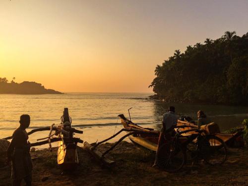 a group of people standing on a beach with a boat at Casa Vana Hiriketiya in Hiriketiya