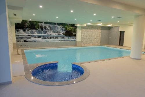 a large swimming pool with a waterfall in the background at Hotel Rekic in Bihać