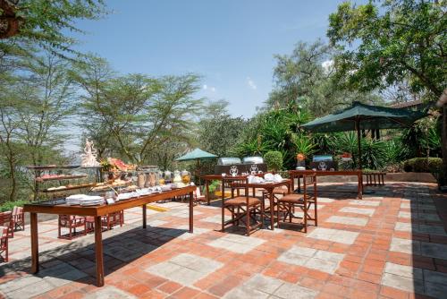 a patio area with tables, chairs and umbrellas at Sarova Lion Hill Game Lodge in Nakuru