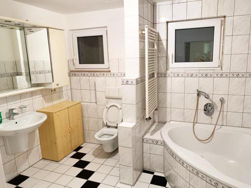 a bathroom with a toilet and a tub and a sink at My-Skypalace Neckarsulm in Neckarsulm