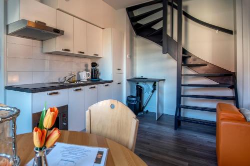 a kitchen and dining room with a table and a spiral staircase at Stadslogement Bij de Sassenpoort in Zwolle