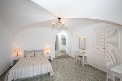 a white bedroom with a bed and a table and chairs at Santorini View Studios - Firostefani Caldera in Firostefani