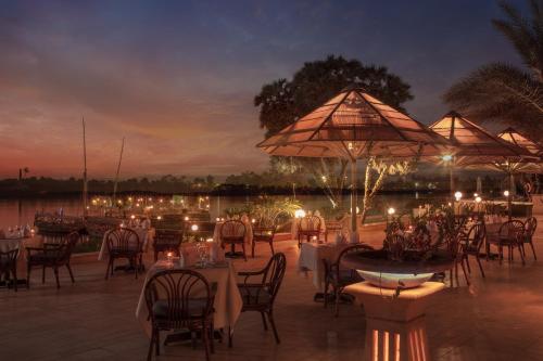 a restaurant with tables and chairs and umbrellas at night at Jolie Ville Hotel & Spa Kings Island Luxor in Luxor