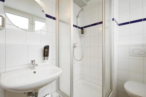 a white bathroom with a sink and a shower at a&o Düsseldorf Hauptbahnhof in Düsseldorf