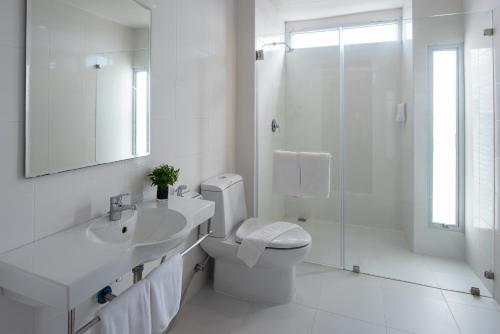 een witte badkamer met een toilet, een wastafel en een douche bij Eco Inn Prime Nakhon Si Thammarat in Nakhon Si Thammarat