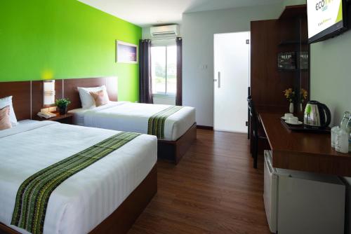 een hotelkamer met 2 bedden en een groene muur bij Eco Inn Prime Nakhon Si Thammarat in Nakhon Si Thammarat