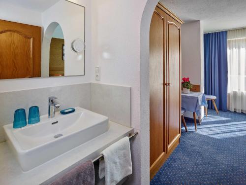 ein Bad mit einem Waschbecken und ein Zimmer mit einem Tisch in der Unterkunft Kristiania in Sölden