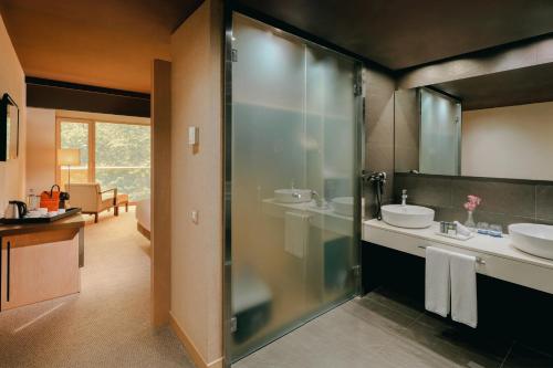 a bathroom with two sinks and a glass shower at Hesperia Bilbao in Bilbao