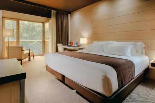 een hotelkamer met een groot bed en een bureau bij Hesperia Bilbao in Bilbao