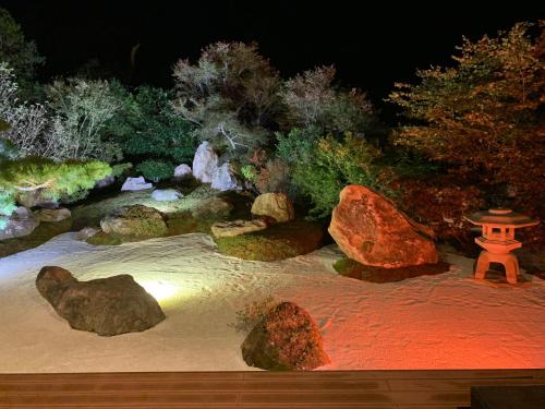 a japanese garden at night with a lantern and rocks at Onsen & Garden -Asante Inn- in Hakone